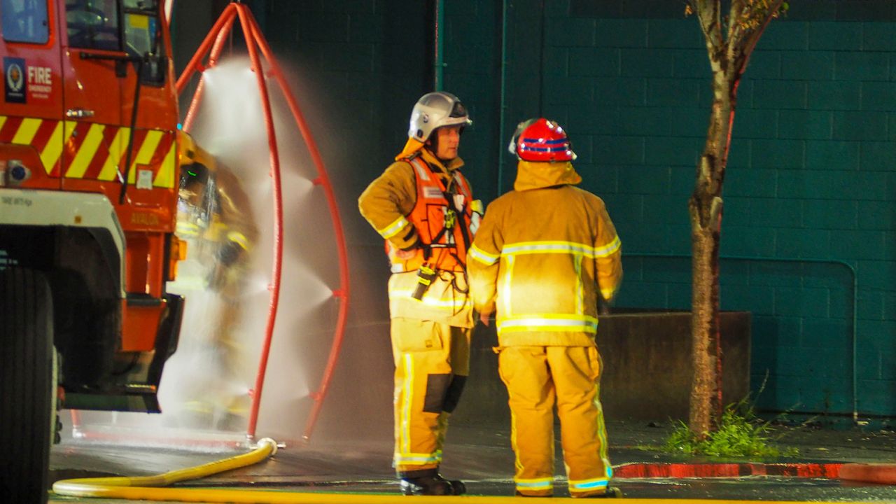 Firefighters stand outside the hostel where a fire broke out overnight. 