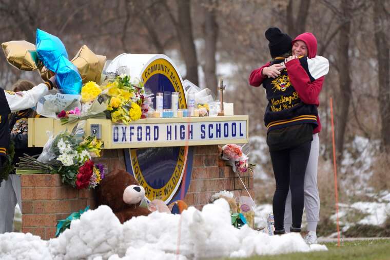 Students hug at a memorial on Dec. 1, 2021, following a shooting at Oxford High School in Oxford, Mich.