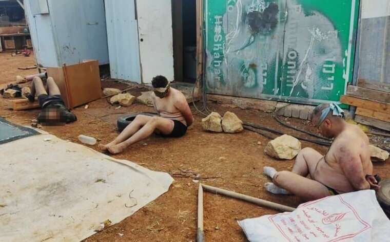 Three men stripped, bound and confined in an animal pen.