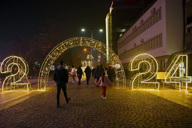 Pedestrians walk through an illuminated 2024 sign in downtown Pristina ahead of the New Year's celebrations in Kosovo on Saturday.