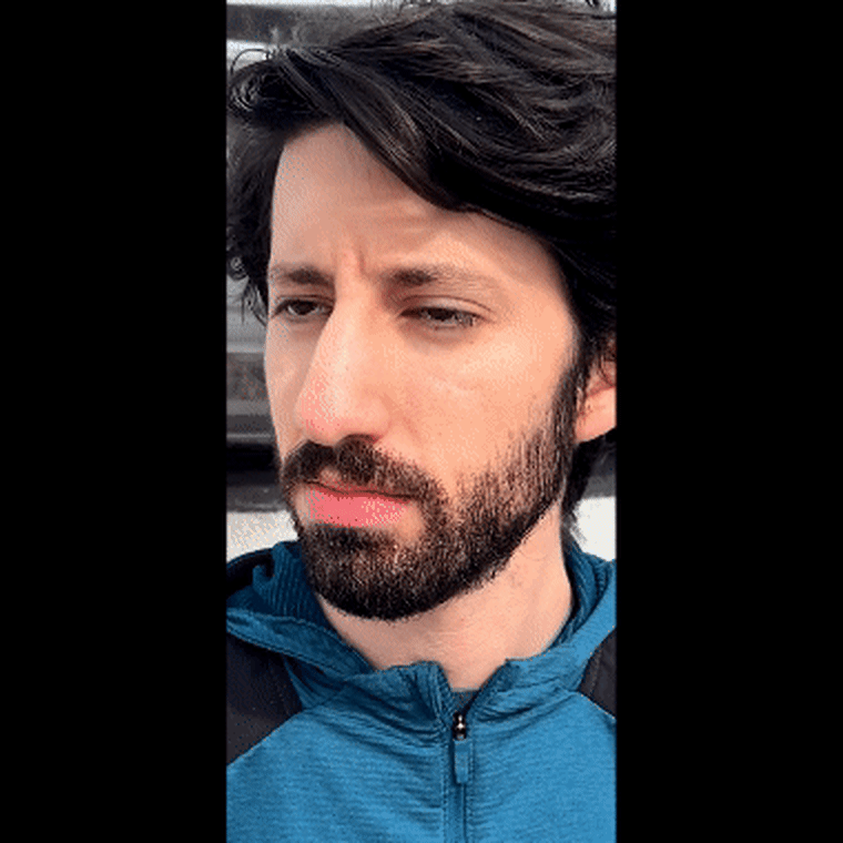 Close-up GIF of the reporter putting the Bose Ultra Open Earbuds in his ears, one at a time.