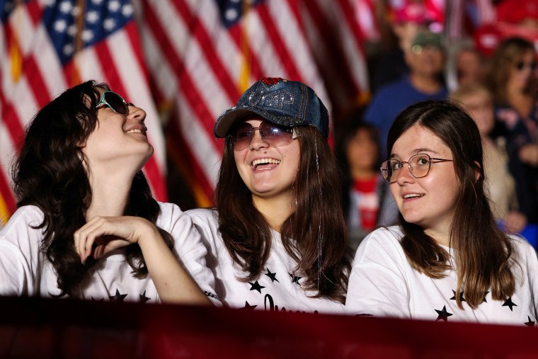Three supporters smile at a Trump rally.