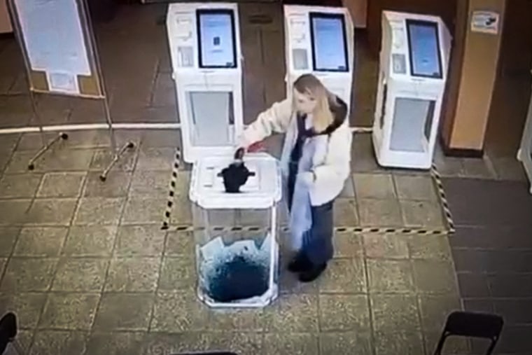A woman pours a liquid into a ballot box, during the Russian presidential election in Moscow.