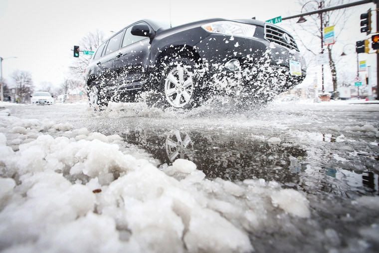 A car passes through snow on Clark Avenue after a snowstorm