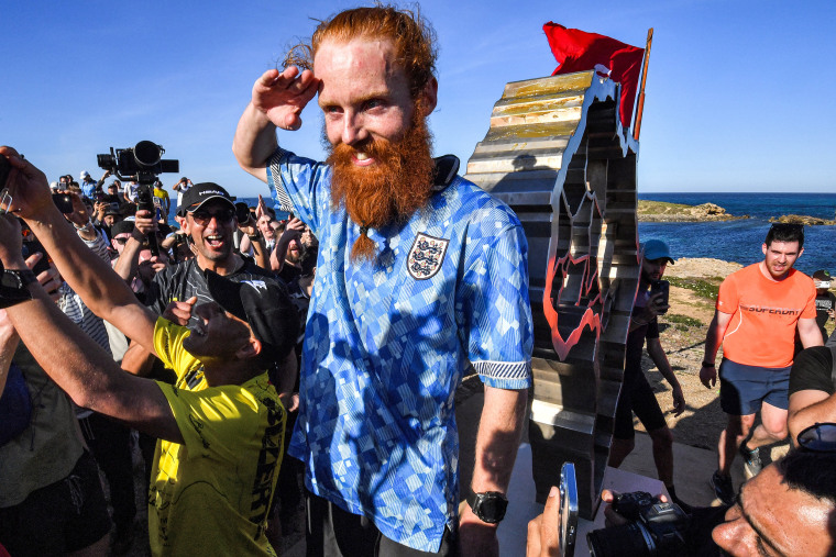 British runner Russ Cook poses for a picture with the memorial sign marking the northern-most point of Africa upon arrival at Cape Angela, northeast of Tunis, on April 7, 2024.