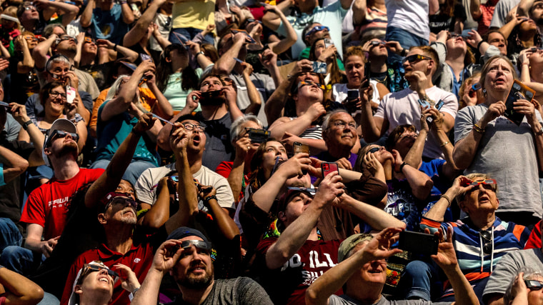 People look at the sky at Saluki Stadium during the total solar eclipse in Carbondale, Illinois
