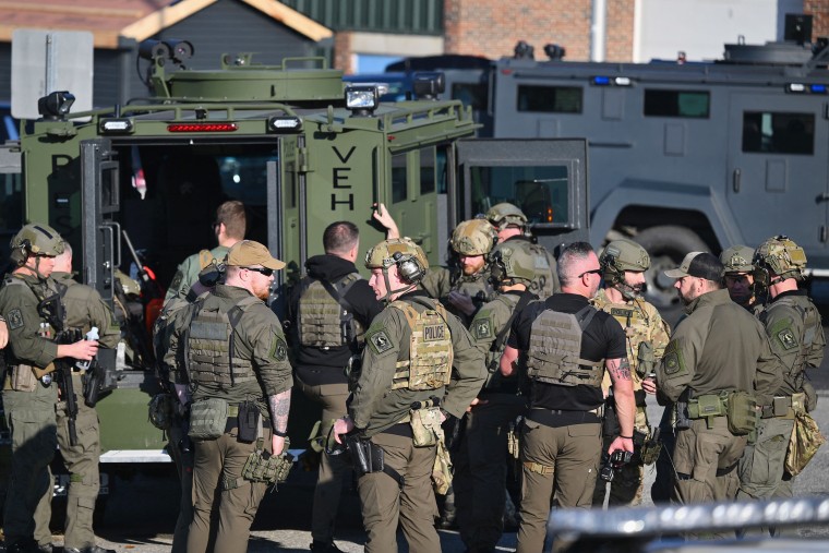 Law enforcement officials gather near their vehicles 